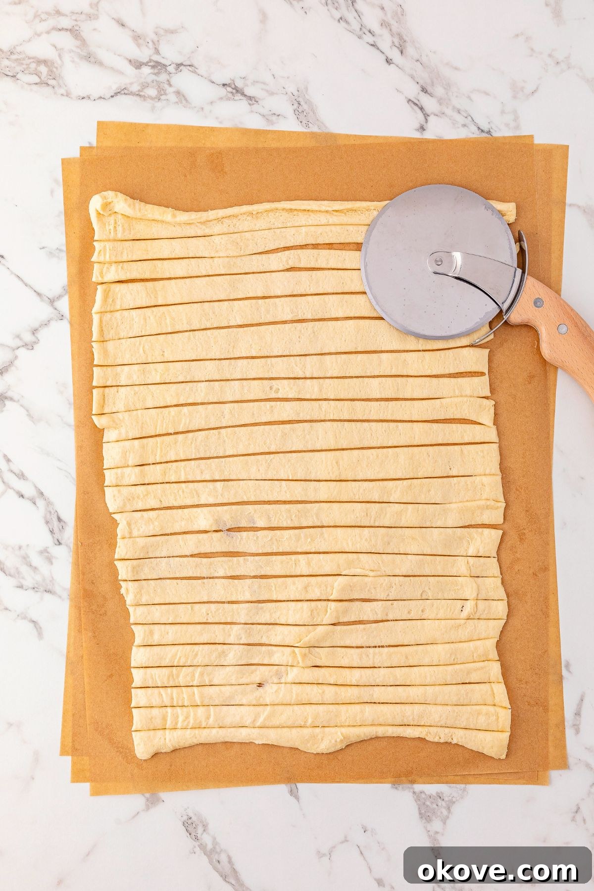 Mummy Hot Dogs 4 Crescent dough unrolled and precisely cut into uniform, thin strips with a pizza cutter, ready for wrapping.