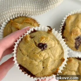 A hand holding a freshly baked flourless peanut butter banana muffin
