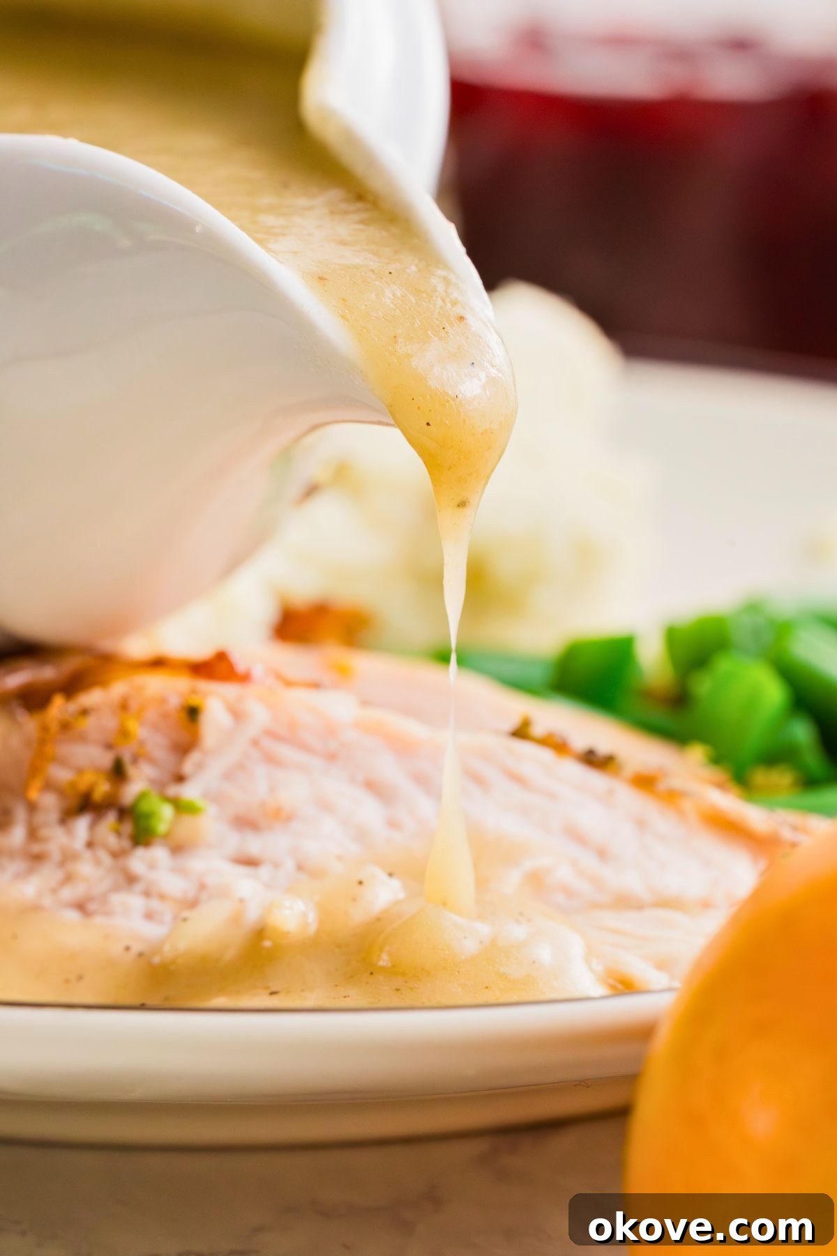 From Pan Drippings to Perfection 7 Homemade gravy being poured over slices of turkey, on a white plate.