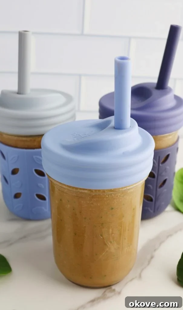 Three sippy cups filled with a rich chocolate spinach milkshake, complete with straws, ready for enjoyment.