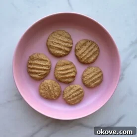 Several 3 ingredient peanut butter cookies on a pink plate, ready to be enjoyed.