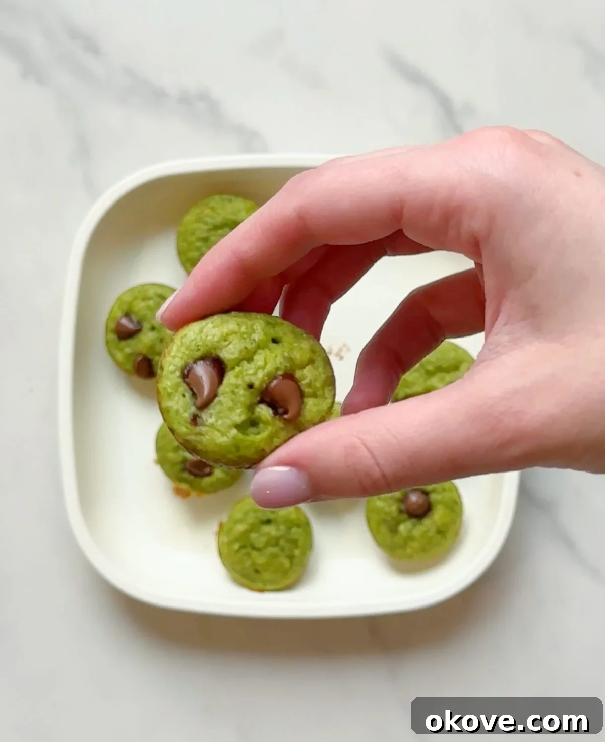 Savory Spinach Muffins 2 A child's hand holding a vibrant green spinach muffin, ready to be enjoyed as a healthy, nutritious snack.