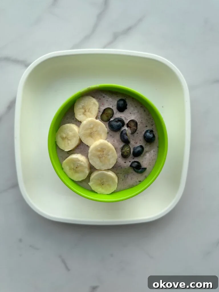 Vibrant Blended Bowls 2 A vibrant smoothie bowl generously topped with sliced fresh bananas and plump blueberries, ready for a healthy breakfast.