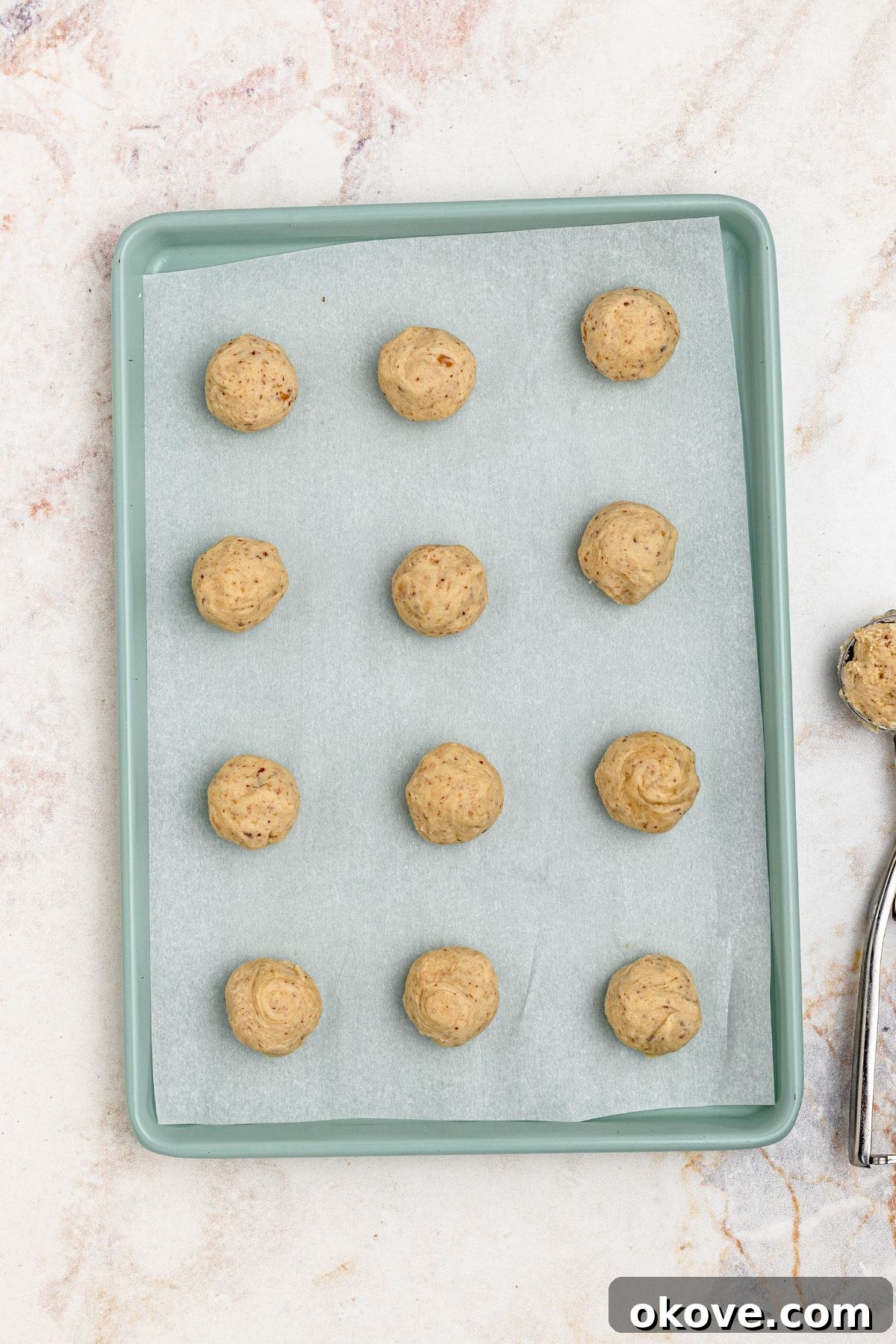 Powdered Cloud Kisses 6 Cookie dough rolled into balls and placed on a parchment paper lined baking sheet, ready for baking.