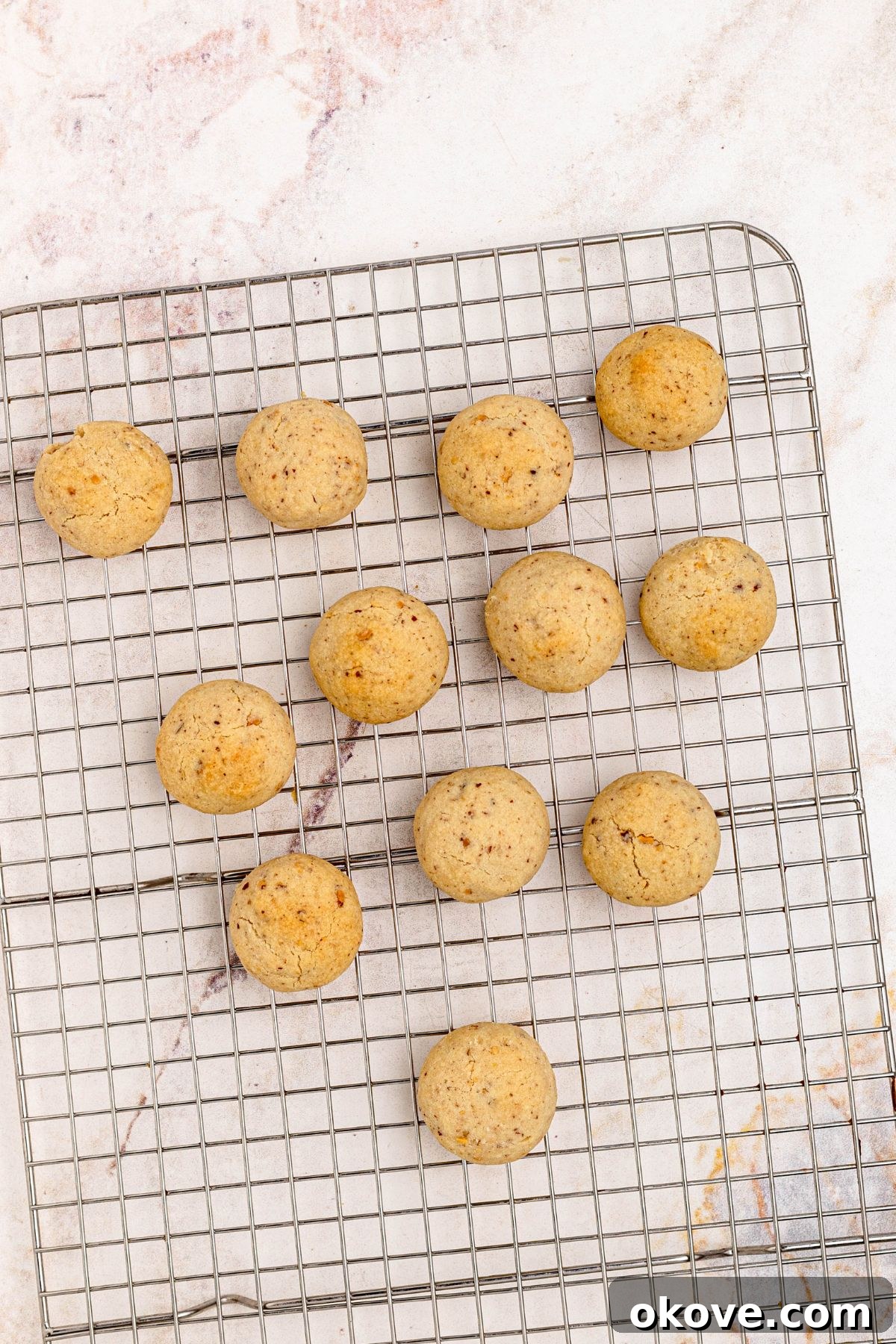 Powdered Cloud Kisses 8 Baked cookies cooling on a wire rack, before dipping into powdered sugar.