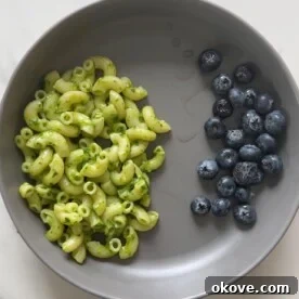 Vibrant Spinach Pesto 3 Close-up of vibrant green spinach pesto in a small bowl, garnished with a few fresh blueberries.