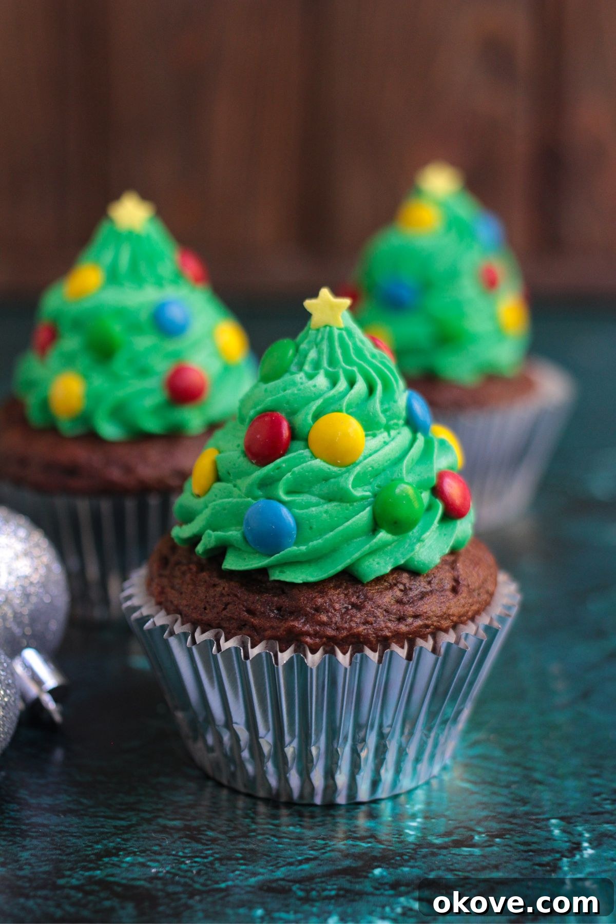 Edible Christmas Trees 2 Chocolate cupcakes, frosting with green buttercream swirls in the shape of trees, decorated with mini candies for lights and star sprinkle for topper.