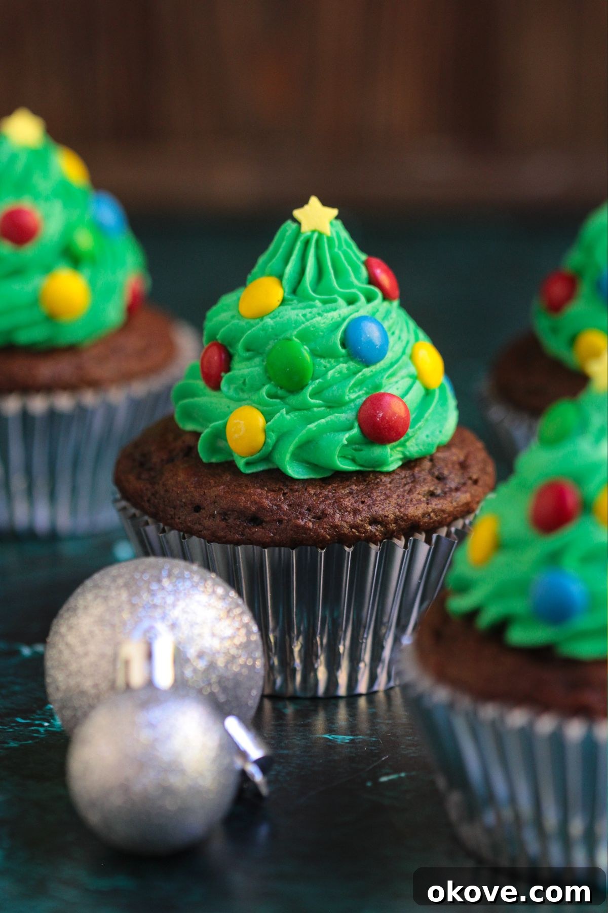 Edible Christmas Trees 8 Chocolate cupcakes, frosting with green buttercream swirls in the shape of trees, decorated with mini candies for lights and star sprinkle for topper.