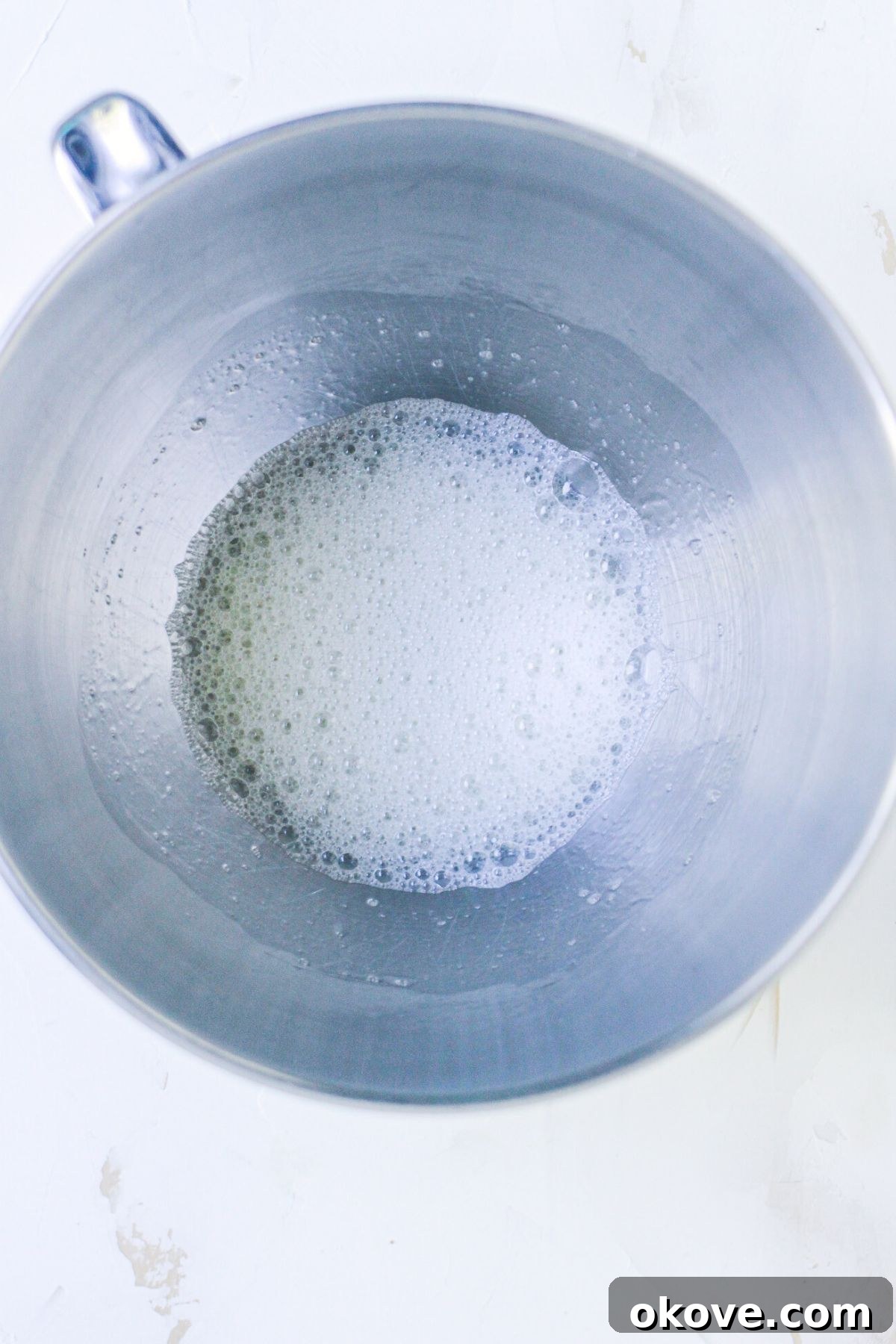 Egg whites in a silver mixing bowl, mixed until foamy. 