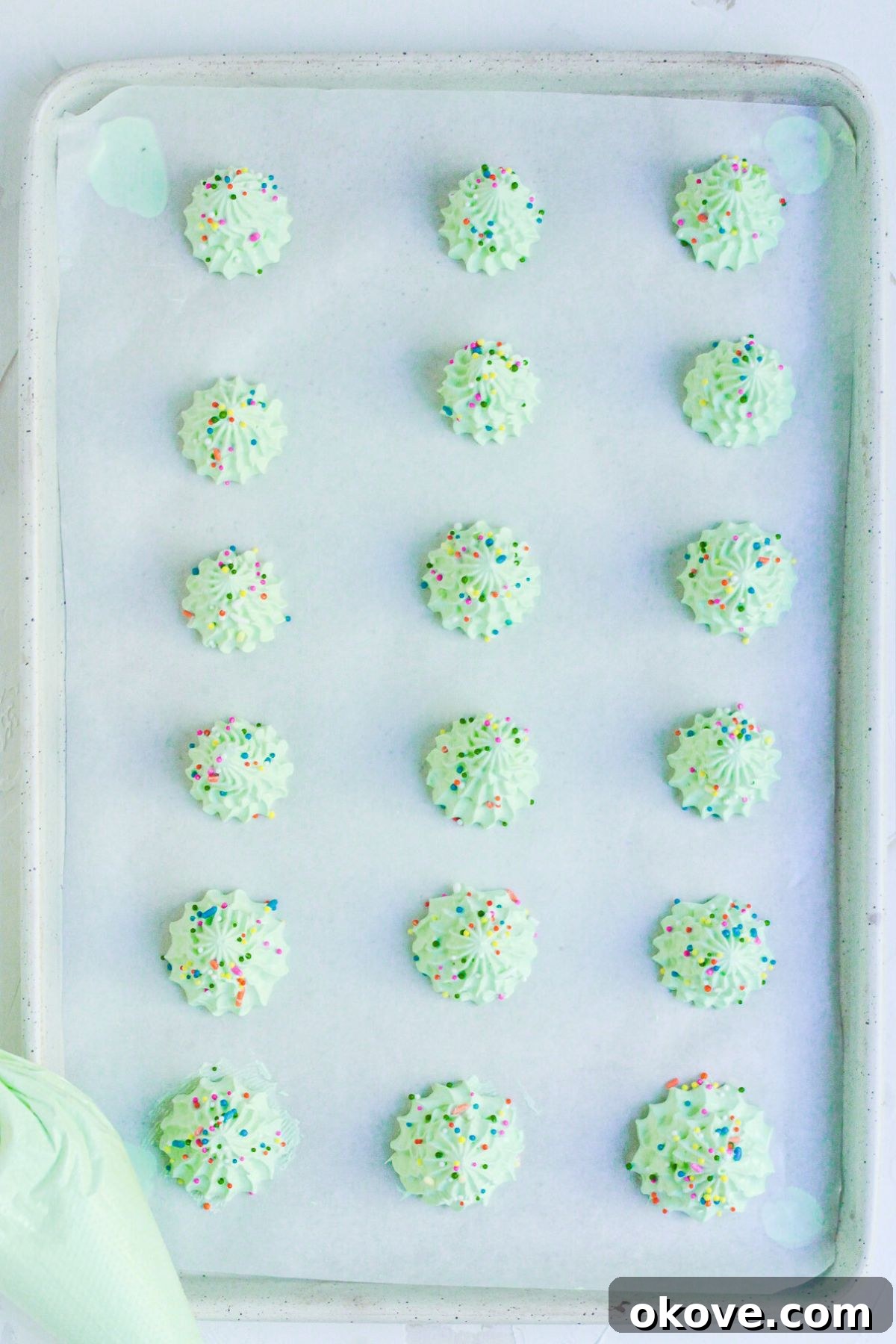 Mini trees piped onto baking sheet, lined with parchment paper and then decorated with sprinkles. 
