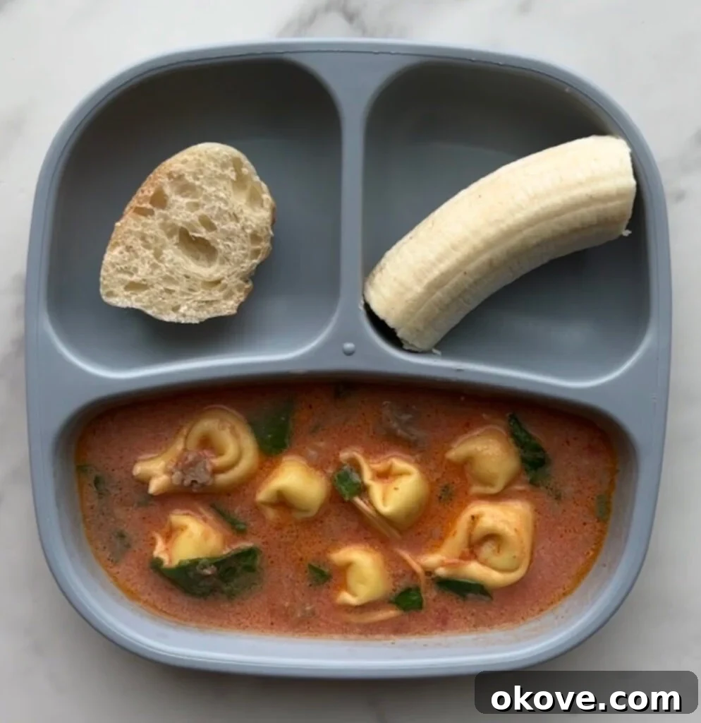 Spinach tortellini soup in a divided plate with half a banana and some bread
