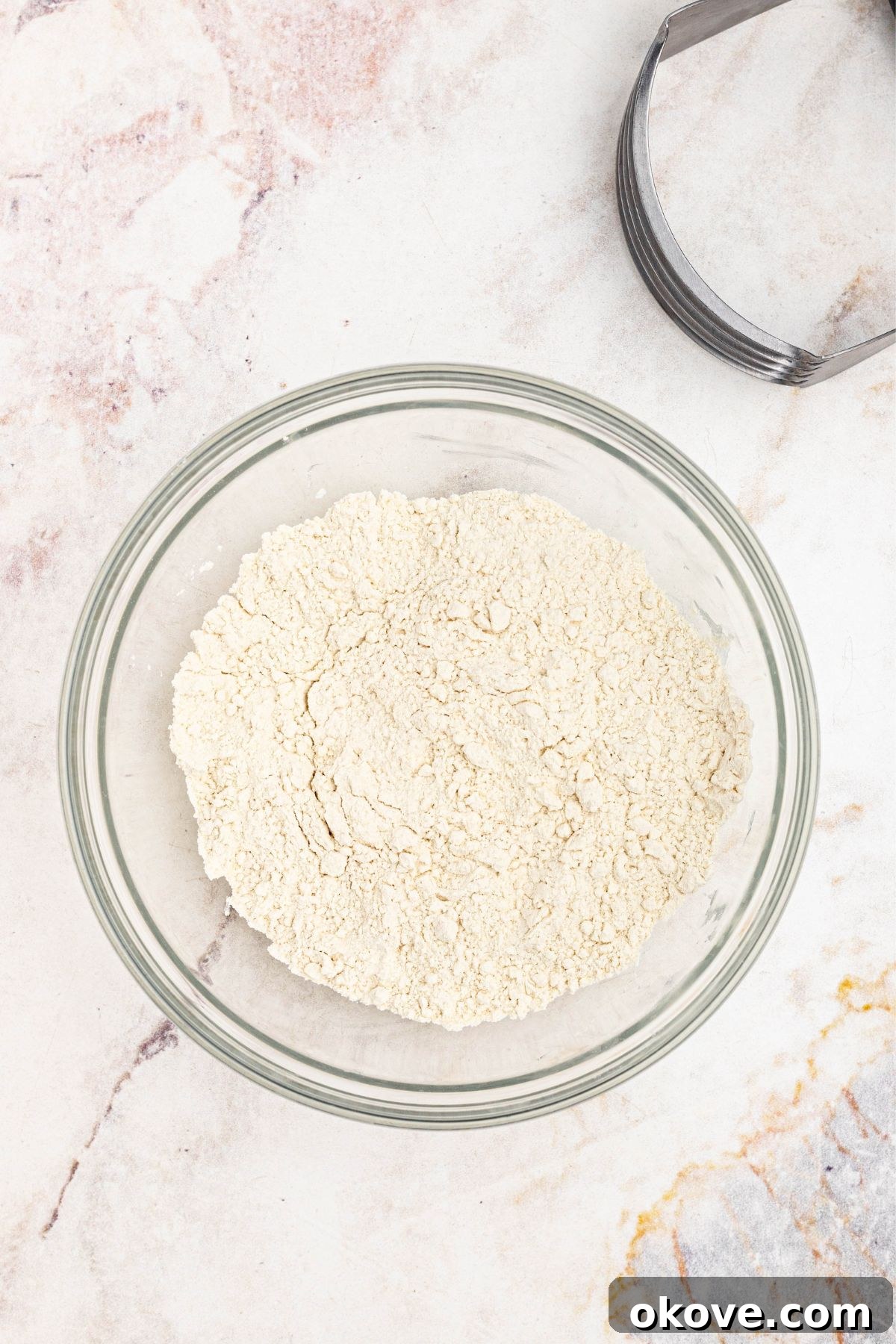Flour, salt, and sugar, mixed together in a clear glass bowl.