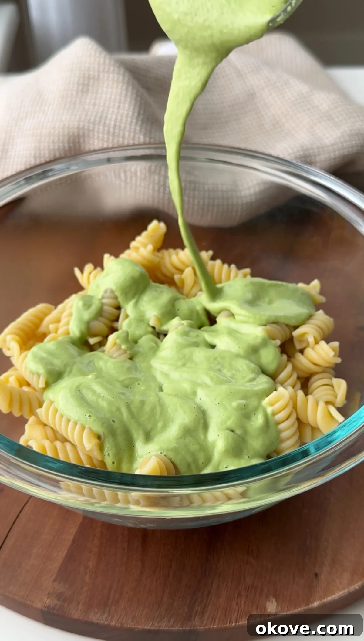Creamy Broccoli Pasta 2 A ladle pouring creamy broccoli pasta sauce into a bowl of perfectly cooked pasta, ready to be served.