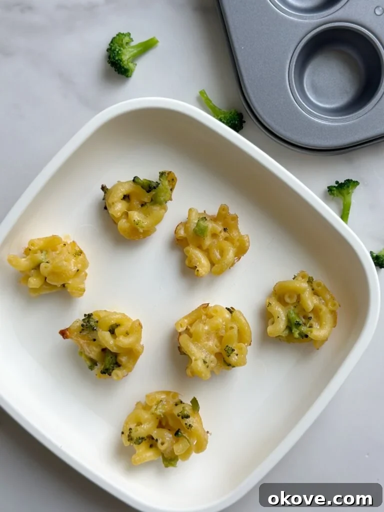 Cheesy Broccoli Mac Poppers 2 Delicious and nutritious bite-sized broccoli mac and cheese snacks on a white plate, perfect for toddlers and kids.