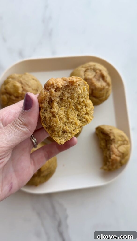 A hand holding up half a healthy sweet potato muffin