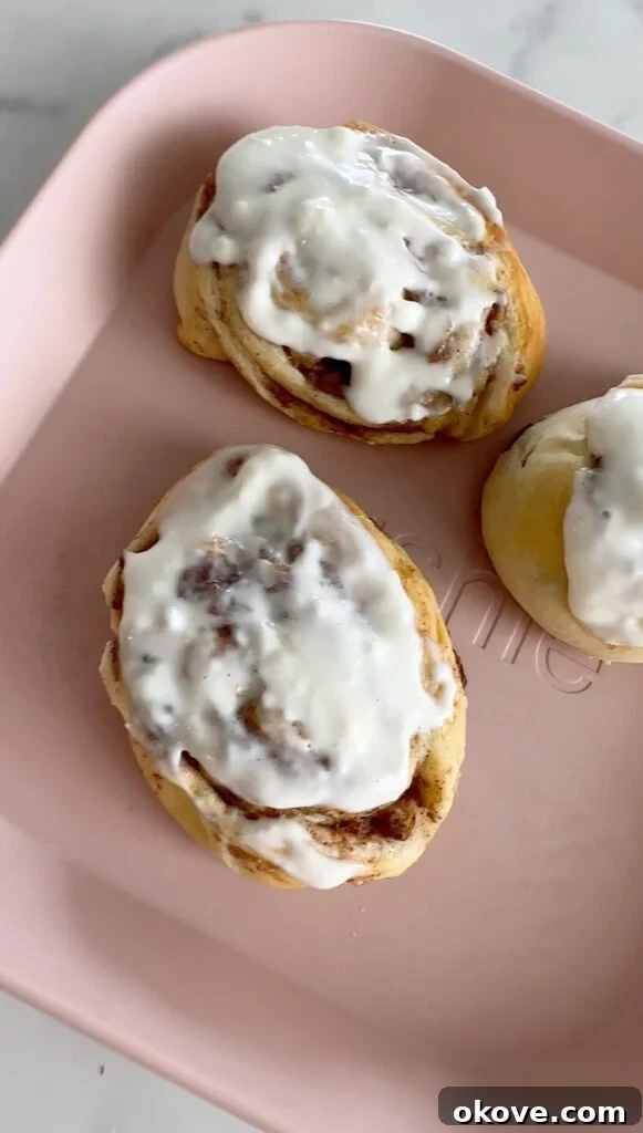 Guilt-Free Cinnamon Swirls 2 Delicious and healthy easy cinnamon rolls with a creamy white icing, served on a pink plate, perfect for a family breakfast.