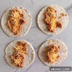 Four bean and cheese burritos on a white background