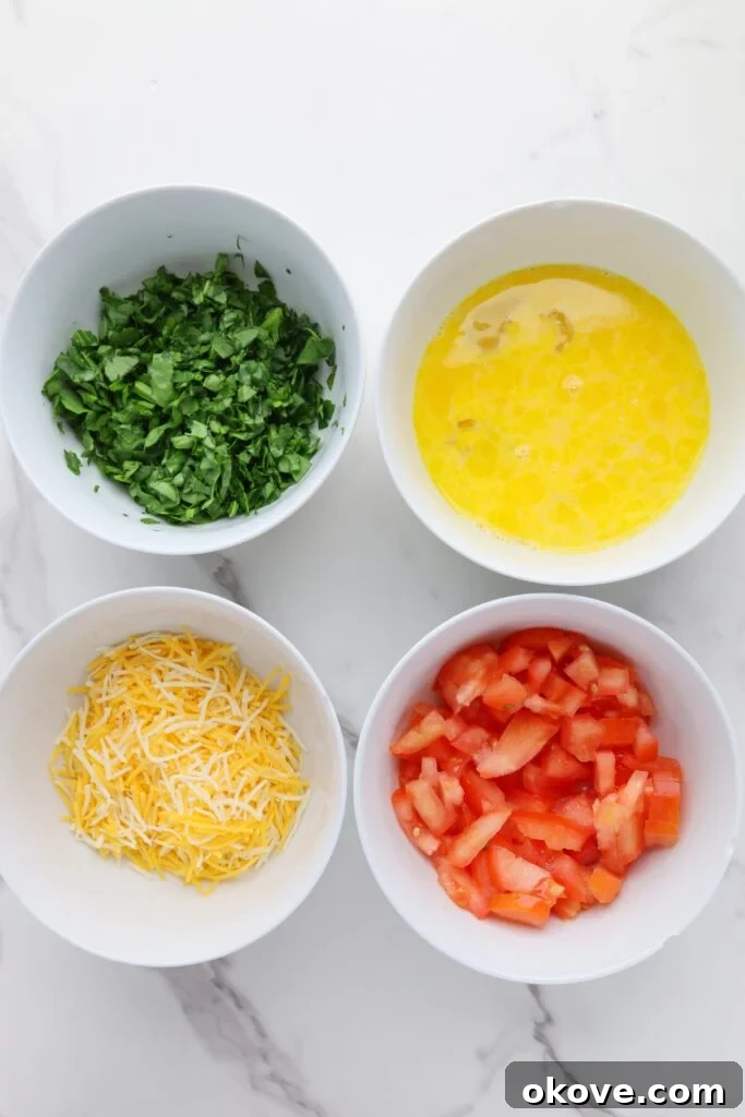 Spinach, eggs, cheese, and tomato in four bowls