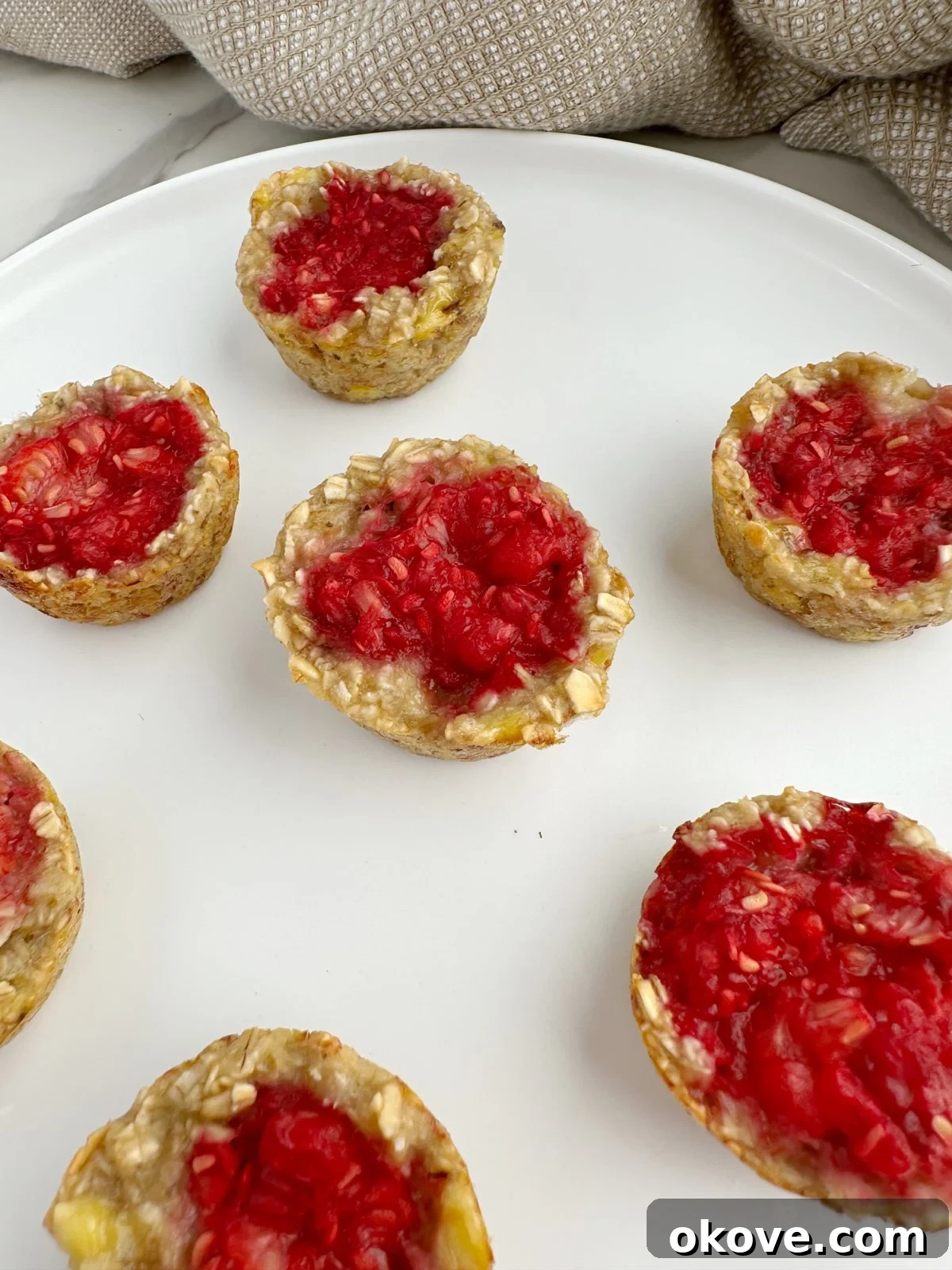 Wholesome Raspberry Oat Bites 4 Baked raspberry oat bites on a white plate, ready to be enjoyed