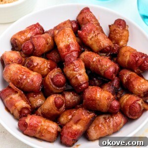 Golden bbq coated bacon wrapped smokies on a white plate with blue glasses of water on the table.