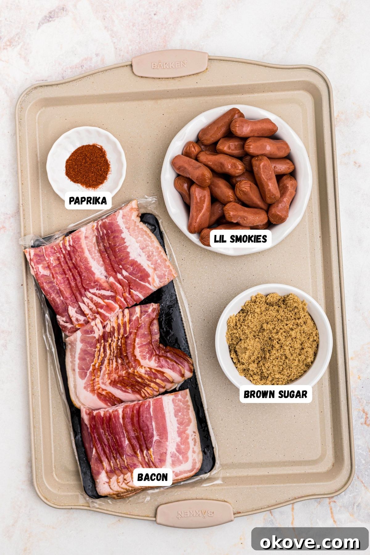 Ingredients of bacon, smokies, brown sugar, and paprika, measured on a baking sheet and labeled. 