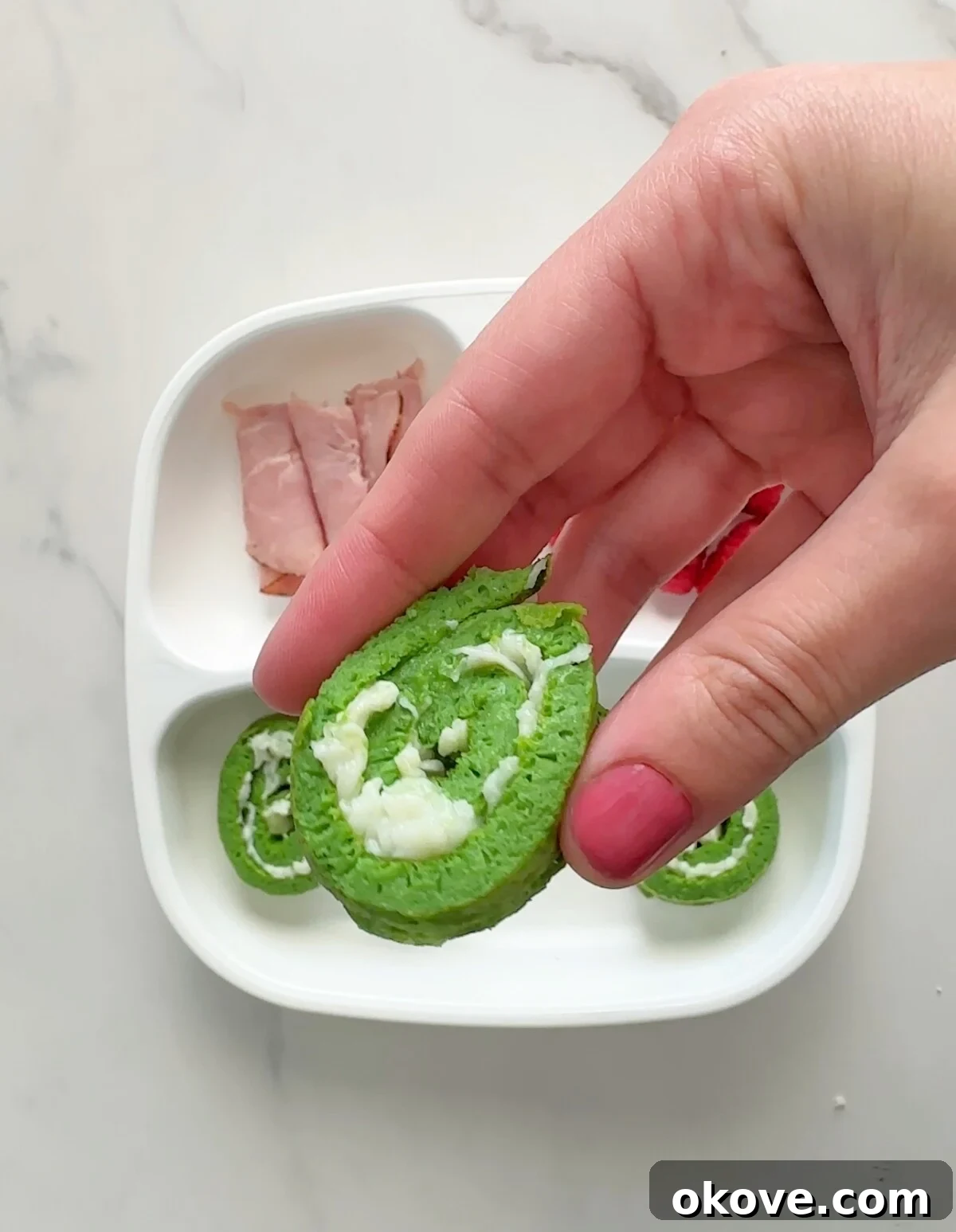 A hand holding a vibrant green Hulk Roll Up, ready to be enjoyed.