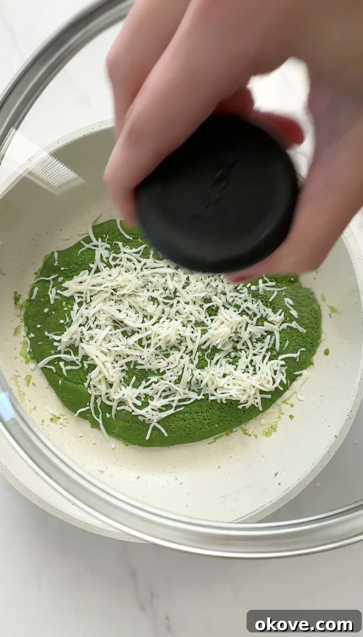 A Hulk Roll Up cooking in a frying pan, topped with melting mozzarella cheese.