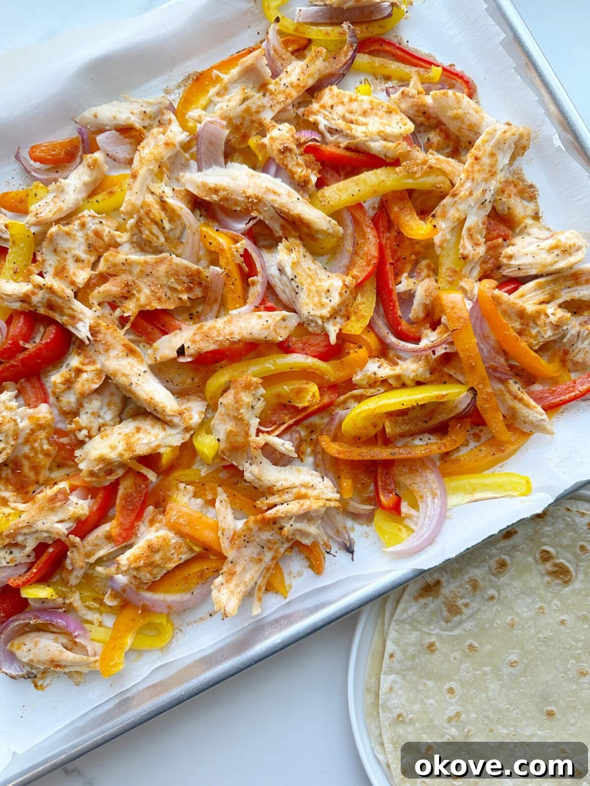 Vibrant chicken and vegetable sheet pan fajitas ready to serve, showcasing colorful bell peppers and onions alongside perfectly seasoned chicken strips on a baking sheet.