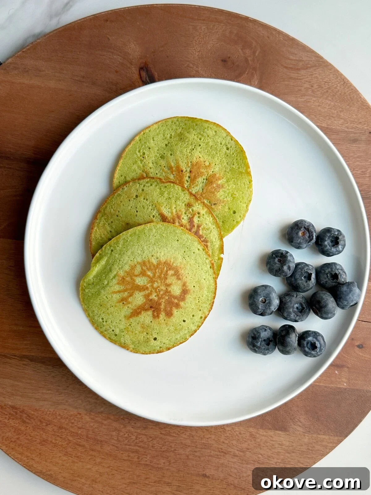 Garden Green Griddlecakes 2 3 spinach pancakes on a plate beside some blueberries