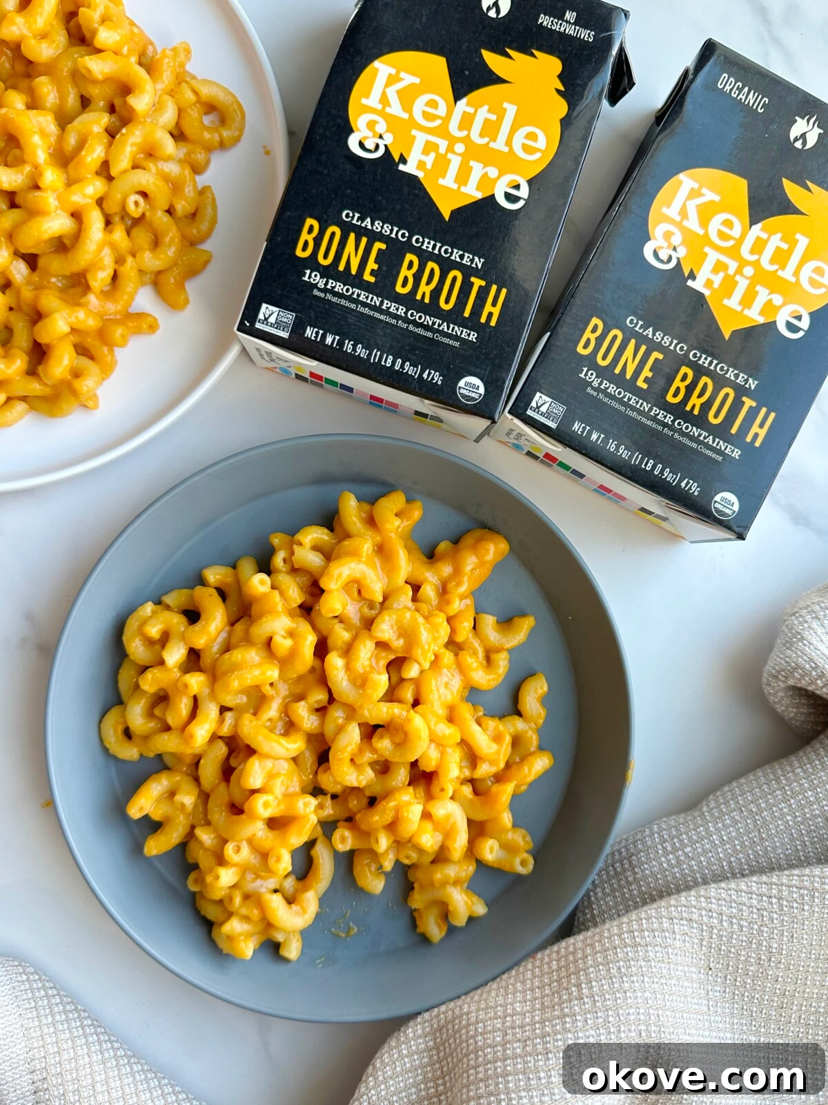 Pumpkin mac n cheese on a plate with two containers of Kettle and Fire bone broth laying beside it