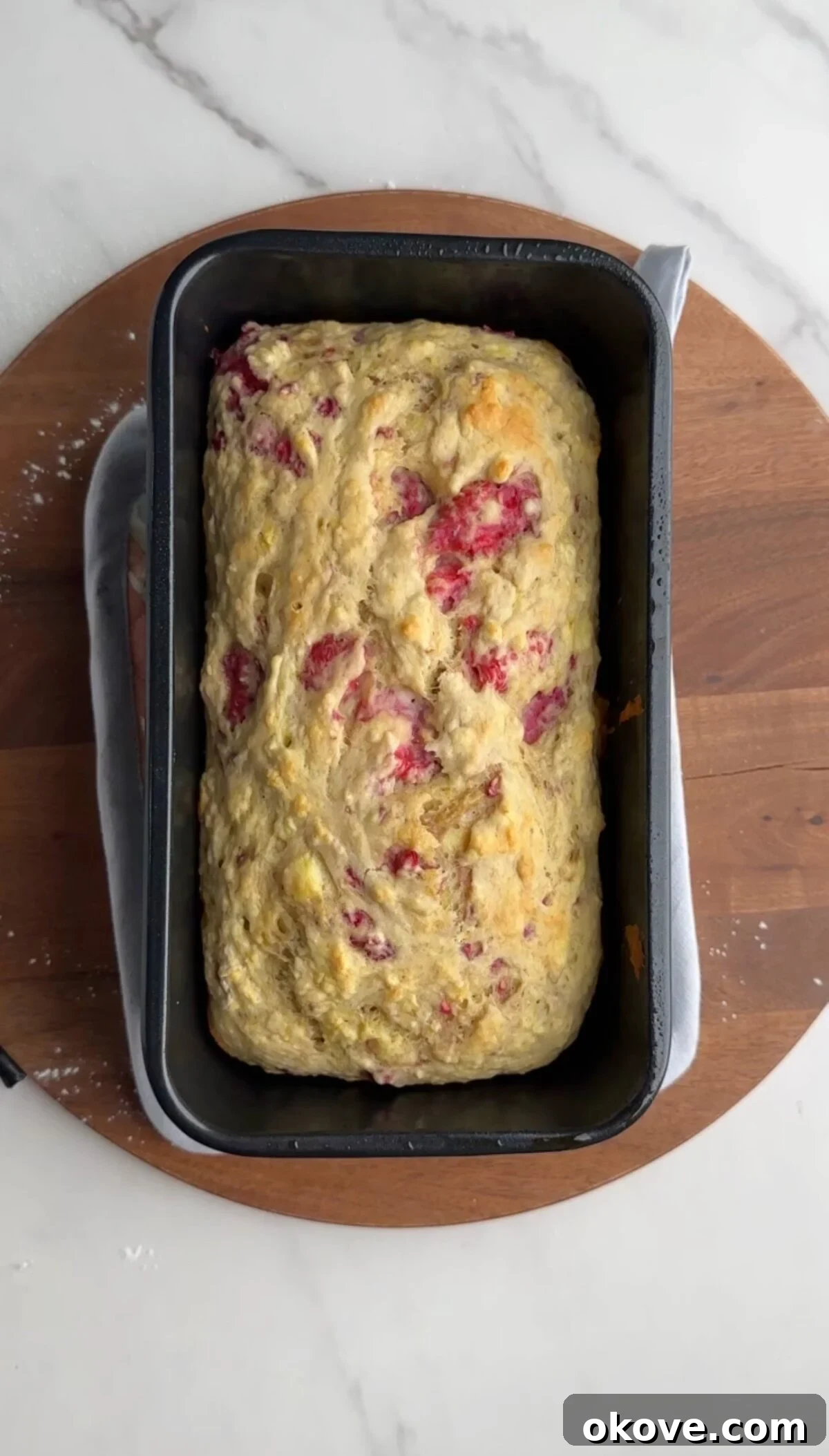 Luscious Raspberry Banana Loaf 3 Freshly baked raspberry banana bread cooling in a loaf pan, steam gently rising.