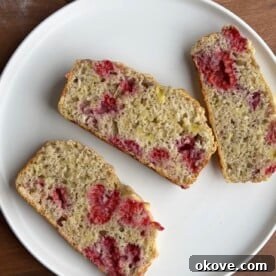 A perfectly baked loaf of raspberry banana bread, ready to be sliced.