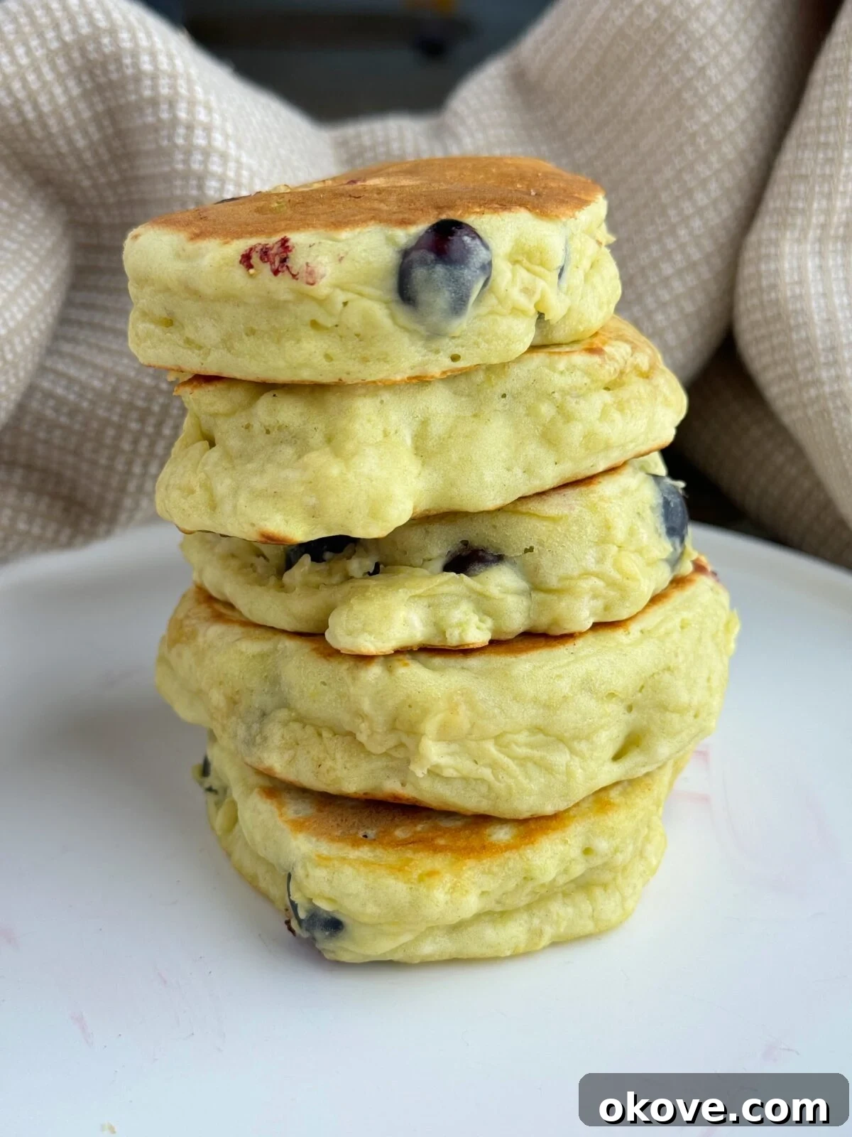 Creamy Banana Avocado Pancakes 2 A stack of golden brown banana avocado pancakes, garnished with a few blueberries, on a white plate, perfect for baby-led weaning or toddler breakfast.