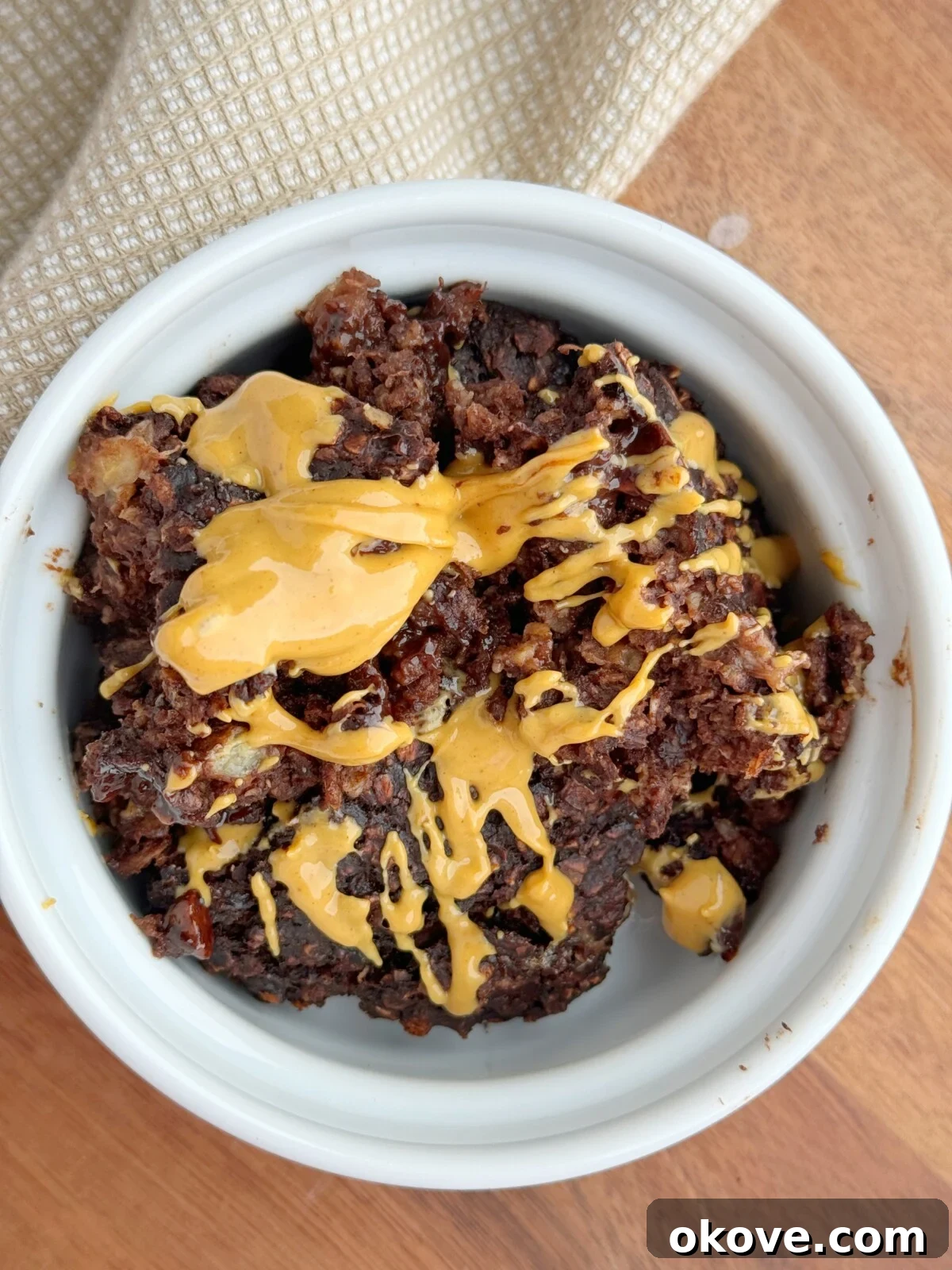 Rich and delicious brownie baked oatmeal in a white baking dish, generously topped with creamy peanut butter, ready to be served for a hearty breakfast.