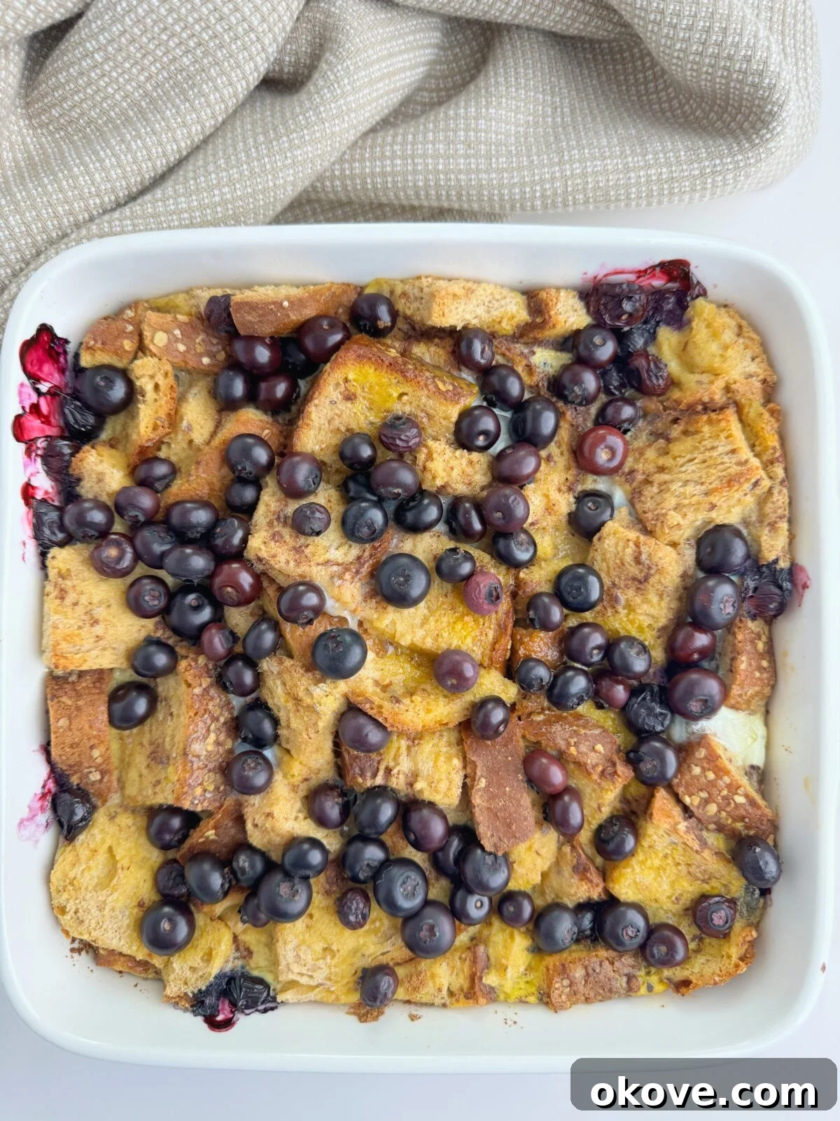 French toast casserole in a dish topped with blueberries and powdered sugar