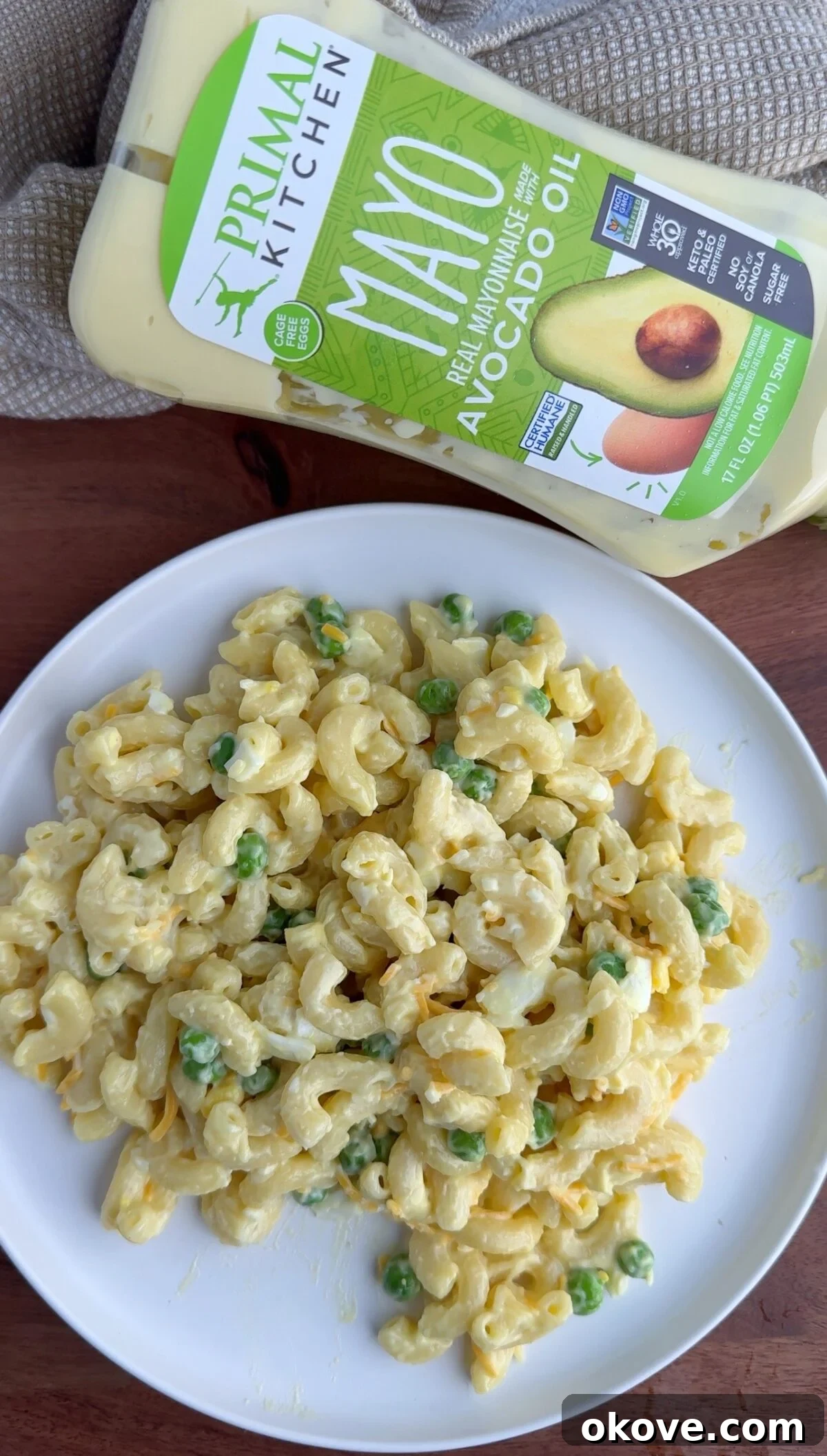 Classic Macaroni Salad 2 Creamy macaroni salad served on a plate, with a bottle of avocado mayonnaise in the background, highlighting its fresh and wholesome ingredients.