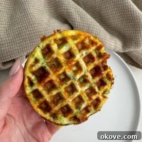A hand holding a healthy broccoli cheese waffle
