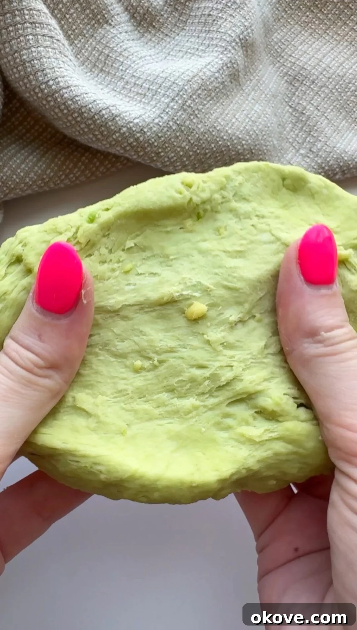 Emerald Avocado Pasta 2 Two hands stretching the avocadough pasta, showcasing its pliable texture and vibrant green color.