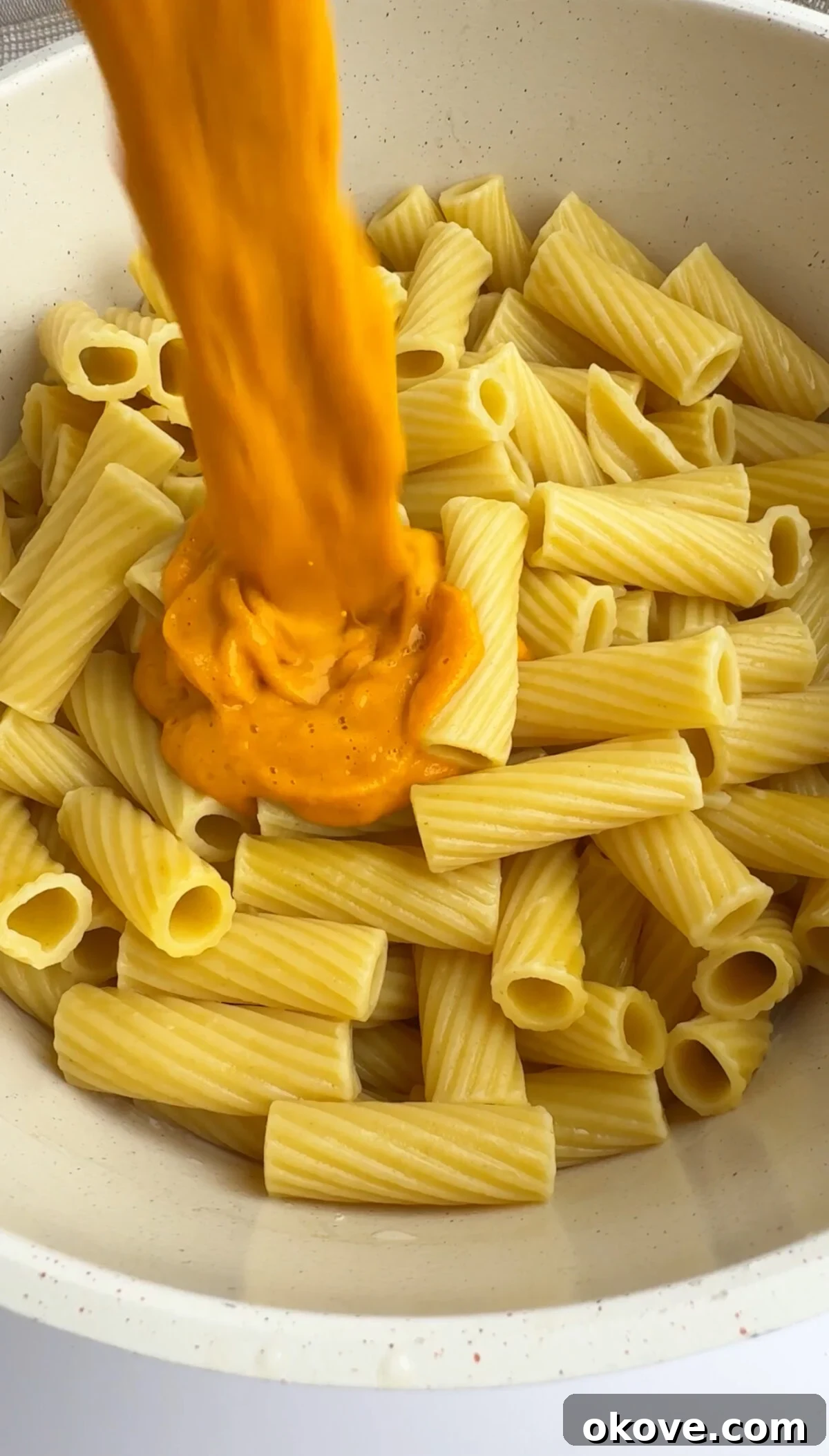 Secret Garden Roasted Pasta 3 Pouring the rich, roasted hidden veggie pasta sauce over freshly cooked pasta in a pot.