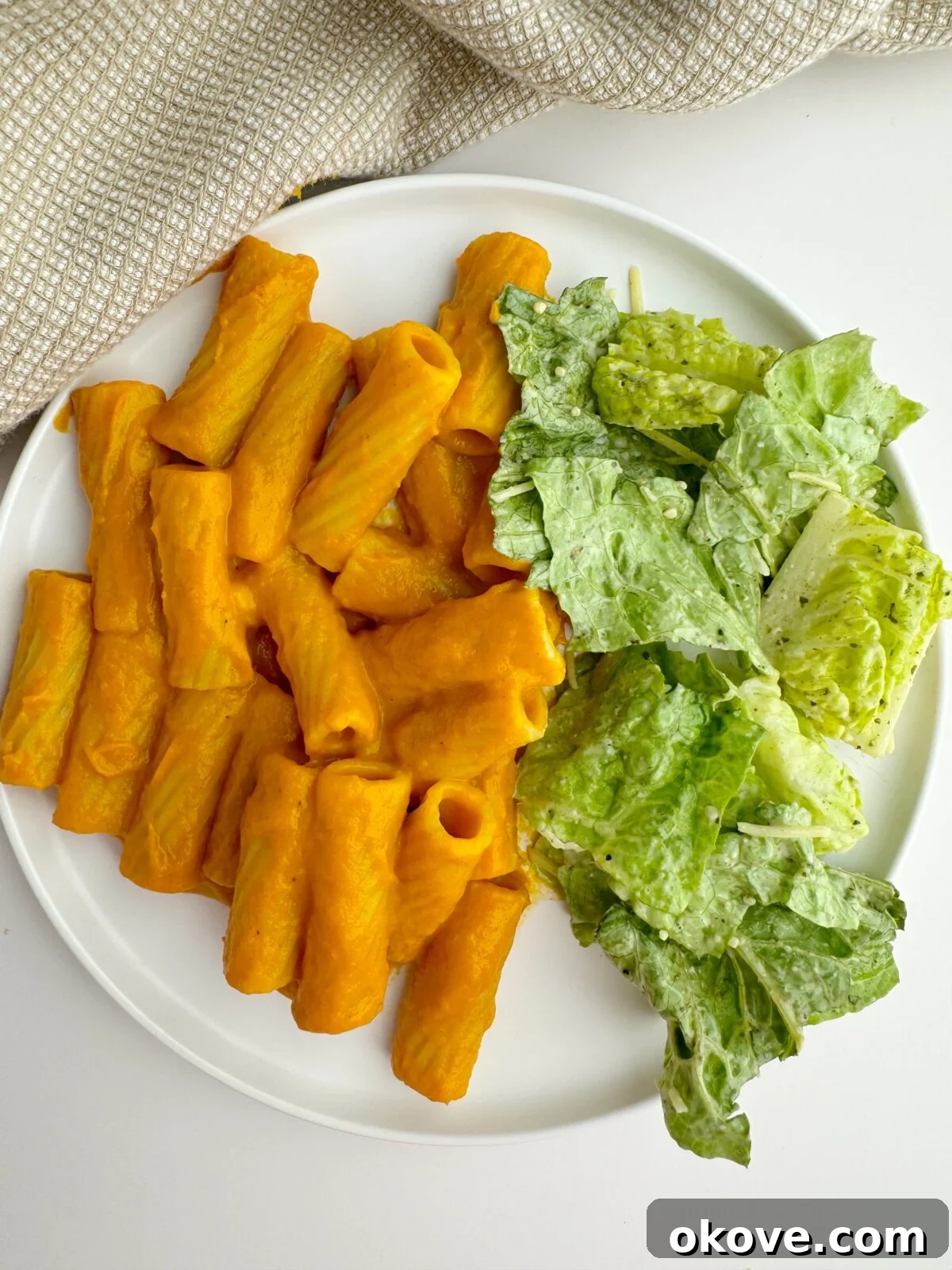 Secret Garden Roasted Pasta 4 The finished roasted hidden veggie pasta served on a plate with a side of Caesar salad.
