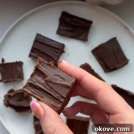 A top-down shot of several pieces of healthy peanut butter chocolate fudge on parchment paper.