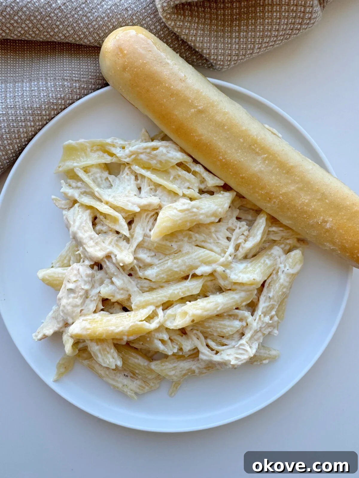Healthy olive garden chicken pasta and an olive garden breadstick on a plate