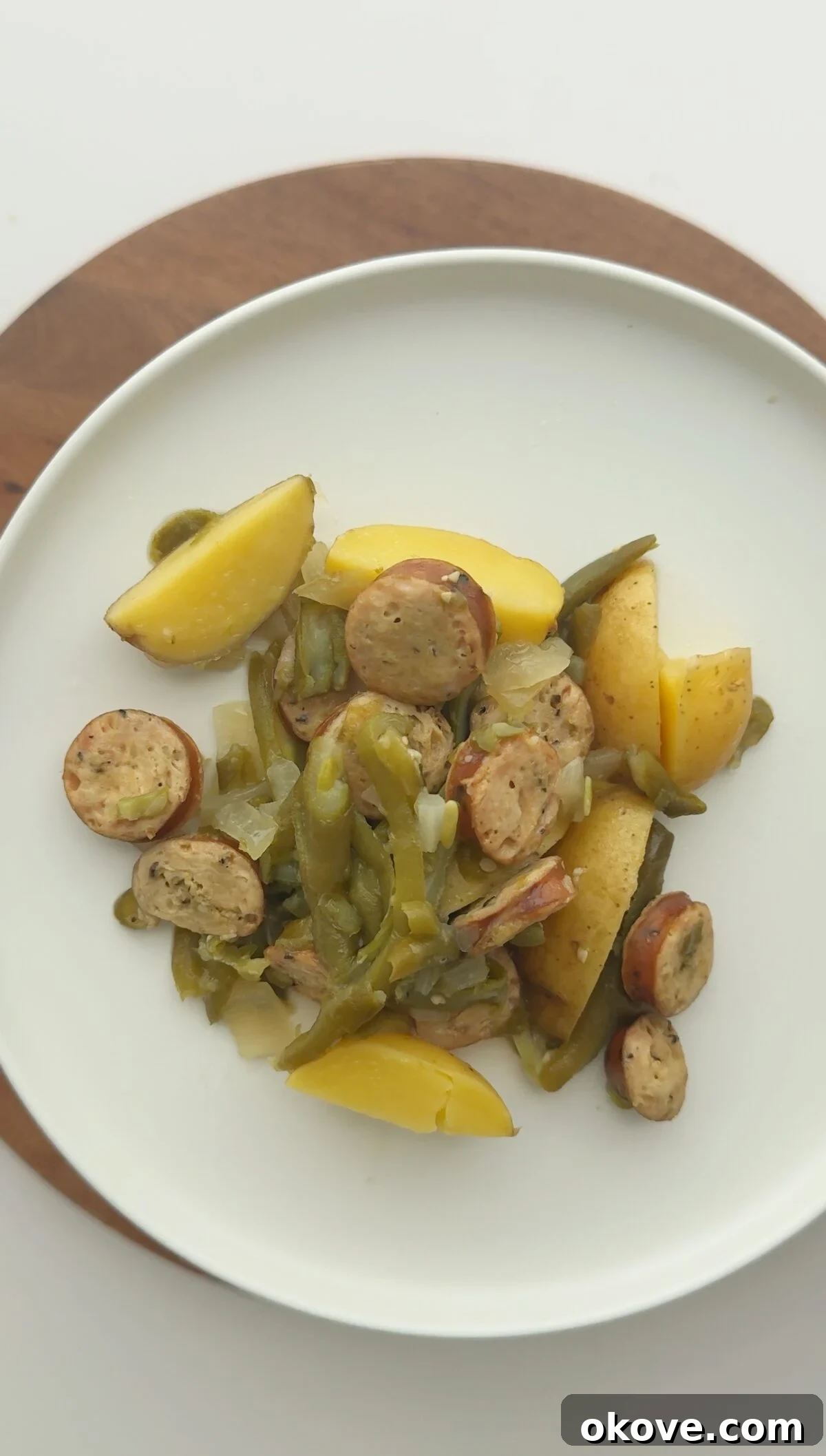 Set-It-and-Forget-It Sausage and Potato Slow Cooker 2 Slow cooker sausage and potato dinner on a white plate, garnished with fresh herbs