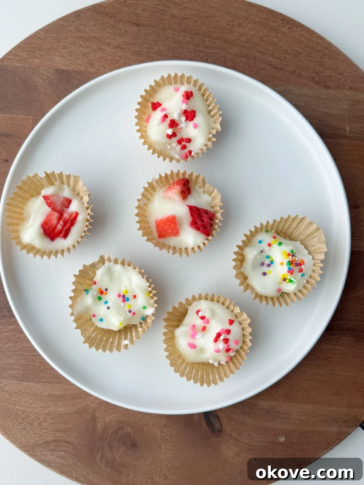 Granola Yogurt Energy Bites 2 Several yogurt granola bites on a white plate topped with strawberries or sprinkles