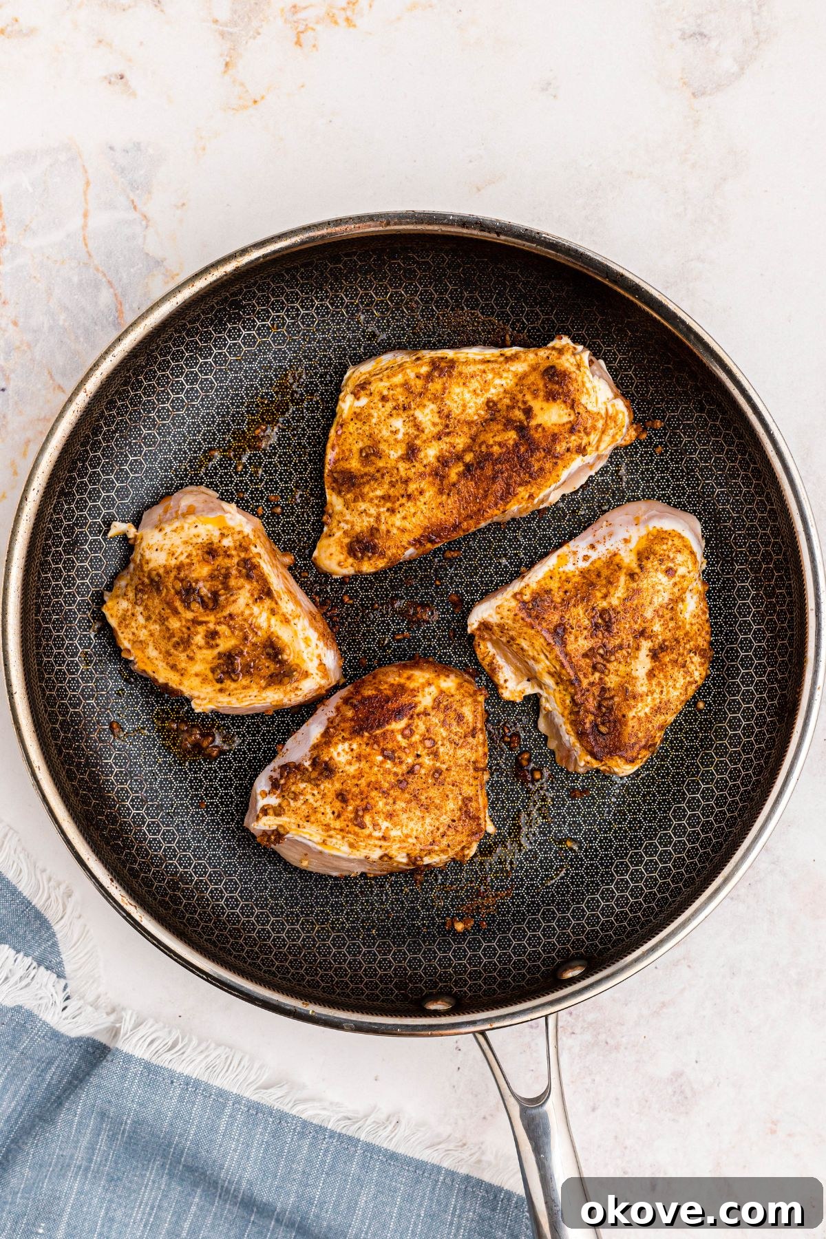 Seasoned chicken seared in a large skillet.