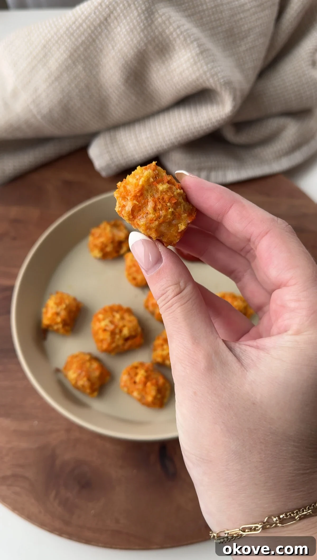 Golden Carrot Cheese Bites 3 A hand holding a cheesy carrot tot