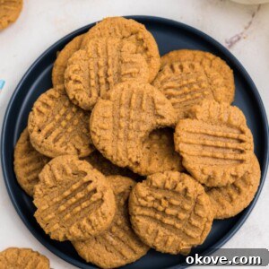 Blue round plate filled with a pile of peanut butter cookies with the top cookie missing a bite.