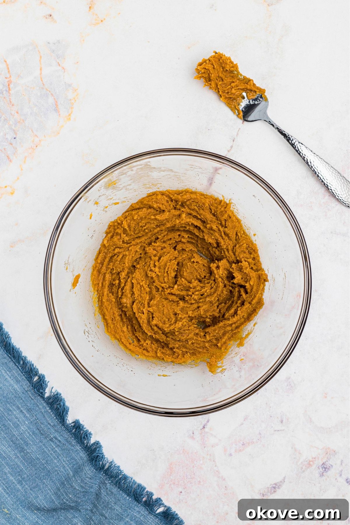 Effortless 3 Ingredient Peanut Butter Bliss 5 Large mixing bowl with creamy peanut butter cookie dough, on a marble table.