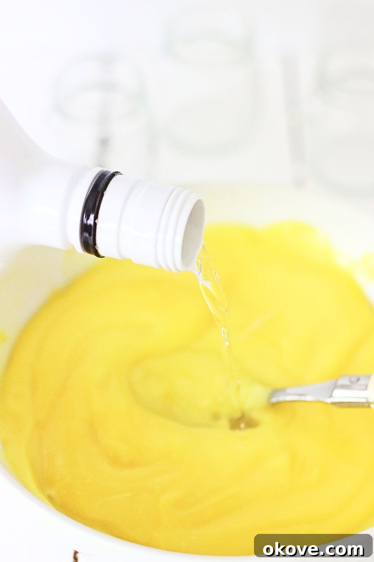 Sweet Banana Pudding Shooters 4 A small white bowl containing banana pudding mix, milk, and Malibu rum being thoroughly mixed with a spoon until smooth and thickened.