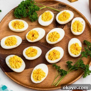 Bright white and yellow deviled eggs, sliced in half, on a round wooden serving platter with parsley garnish.